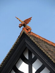 Fototapeta na wymiar Traditional house with wooden structure, roof with ceramic tiles and decorated with a dragon. Historic city of Salisbury. England. United Kingdom.