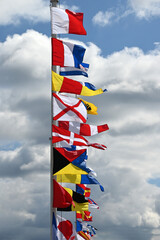 Naklejka premium Signal marine multi colored flags fluttering on flagpoles adorn the sea pier.