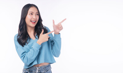 Obraz na płótnie Canvas Cheerful excited asian woman use finger pointing to side with product or empty copy space standing over isolated white background. Model young girl laughing promotion. Advertisement presenting concept