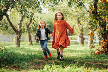 Fototapeta premium Children running , dancing plays on the meadow. Girls having fun. Cute little longhair blonde girl dancing at sunset park. Selective focus