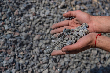 Crushed stones in the hands of a man. Selective focus.