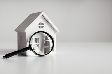 Magnifying glass and house model. House selection and search, real estate concept - obrazy, fototapety, plakaty