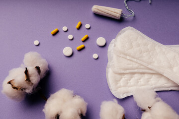 Woman hygiene protection, menstruation, sanitary pads and tampon with pills on purple background