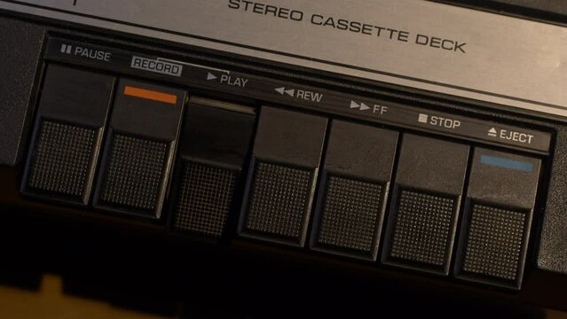 Angled shot of pushing different buttons on a vintage cassette tape player