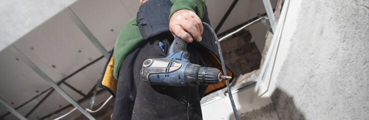 Man holds a drill. Doing home renovation