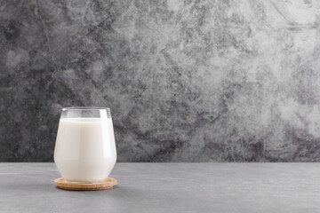 Milk in a glass on grey stone table minimal background with copy space. Lactose free milk made of...