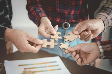 A group of businessmen assemble a jigsaw puzzle. Successful teamwork concept, help and support in business, close up.