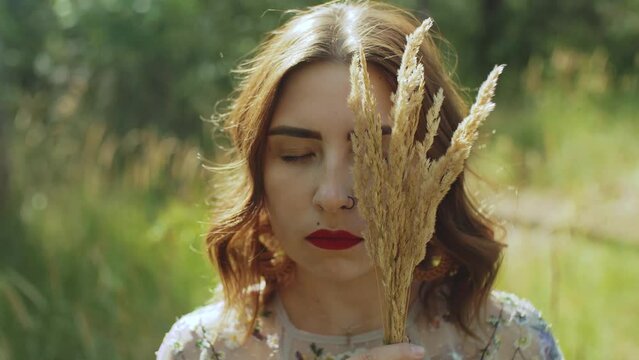 portrait of an attractive woman with closed eyes and a bouquet of spikelets in her hands near the face.