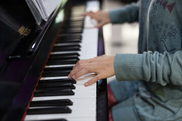 Young woman playing piano at home with closeup hand