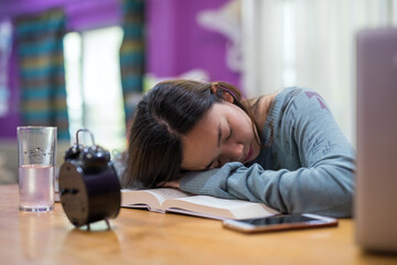 Asian woman sleep after reading text book to prepare for final exam