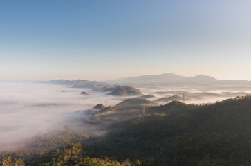 Aerial view Transmission tower in green forest and beautiful morning smooth fog. Energy and environment concept. High voltage power poles. Pang Puay, Mae Moh, Lampang, Thailand.