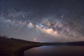 Fototapeta na wymiar Milky Way Galaxy moving over the mountain ridge and lake. Night lapse from night to day. Starry night, Lampang Thailand, night sky stars on sky background.