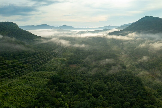 Aerial view Morning scenic on high mountains with electricity pylon Pang Puay, Mae Moh, Lampang, Thailand. Beautiful morning with golden sunrise and fog flowing.