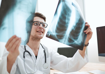 Male doctor radiologist examines x-rays in a medical office.
