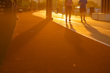 Jogging in the morning. People are running on a park next to a lake during an amazing summer sunrise. Run is a healthy way of living. People and sports.