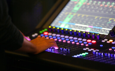 Music tehnician while sound recording studio mixing desk. Sound engineer or music producer working during an event on a digital mixing panel.