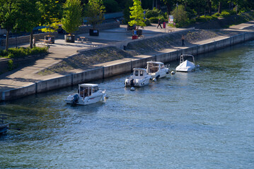 Aerial view over Rhine River with moored motor boats and people walking on boardwalk on a sunny spring day. Photo taken May 11th, 2022, Basel, Switzerland.