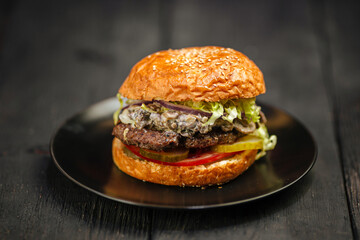 Plate of fresh beef burger on black wooden background