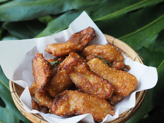 Deep-fried sliced banana and white sesame in basket,Green leaves background.