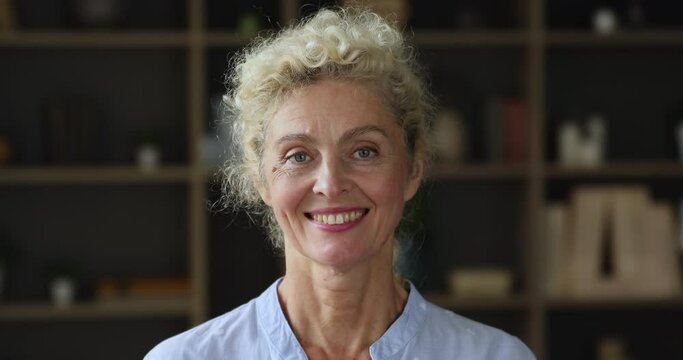 Head shot portrait attractive blonde mature woman pose for camera, standing indoor look at cam having wide toothy smile advertise dental check-up services, medical insurance for older citizen concept