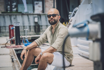 Portrait of a fashion young man posing at marina and yahts background