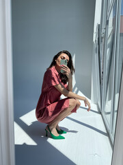 Fit tanned woman in comfy cotton summer long cute dress and green heels, take photo selfie on phone in mirror for social media, stories, vertical.