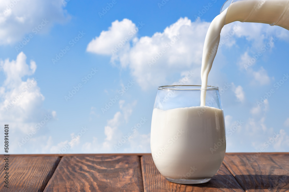 Poster milk pouring from jug into glass on table