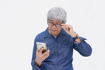 Joyful Asian senior man in denim casual style looking at smartphone and feeling surprised. Online and social network senior lifestyle and concept