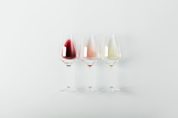 Flat-lay of red, rose and white wine in glasses on white background
