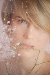 A gentle girl on a pink background, behind fogged glass. Femininity and tenderness, relaxation. Beauty and personal care industry.