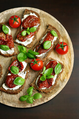 Bruschetta with dried tomatoes and basil. Open sandwiches on rye bread with tomatoes.