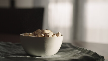 roasted pistachios into white bowl on table