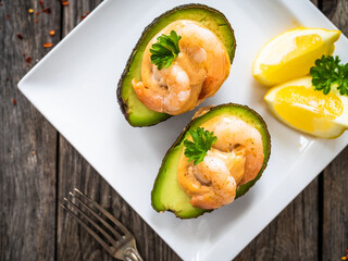 Avocado with fried prawns on and cocktail sauce on wooden background