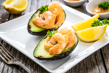 Avocado with fried prawns on and cocktail sauce on wooden background