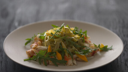 serving fettuccine with crab meat, lemon and arugula on white plate closeup