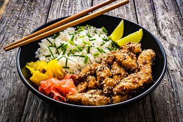 Teriyaki chicken nuggets with rice and vegetables on wooden table
