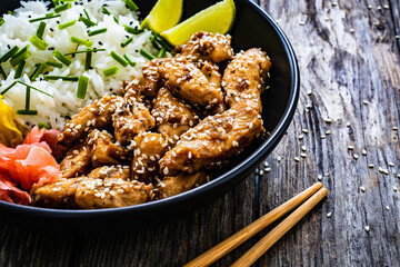 Teriyaki chicken nuggets with rice and vegetables on wooden table
