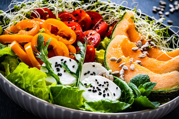 Fresh salad - goat cheese and vegetables on black  wooden table
