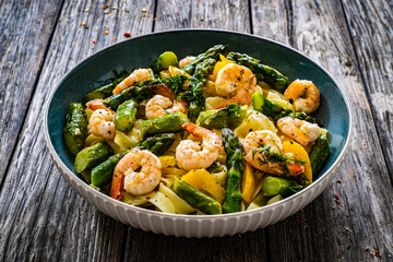 Tagliatelle with prawns and asparagus on wooden table
