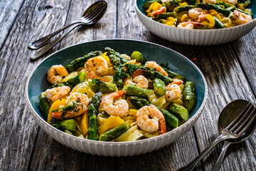 Tagliatelle with prawns and asparagus on wooden table
