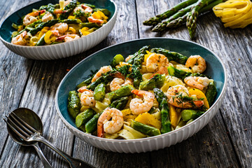 Tagliatelle with prawns and asparagus on wooden table
