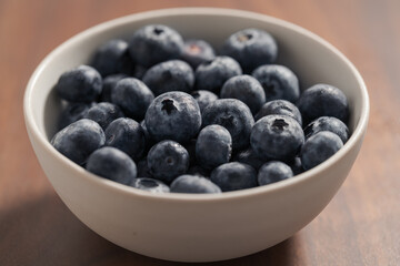 Fototapeta na wymiar fresh blueberries in white bowl on wood table