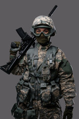 Fototapeta premium Shot of militant woman dressed in uniform with helmet and eyewear holding rifle.