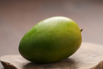 Ripe green mango washed and ready to eat on wood board