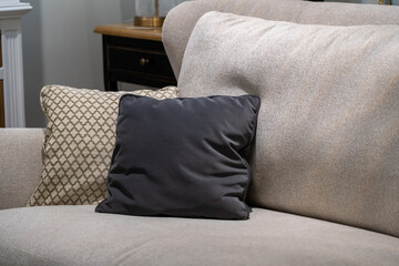 Close up light fabric sofa with dark grey pillow in warm cozy home interior background. Pillows on...