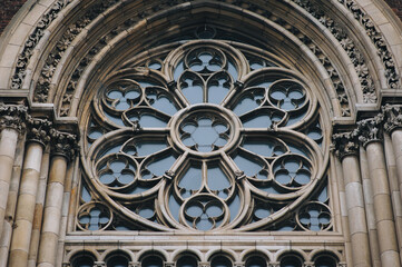 Round openwork window with stained glass on the facade of the building. Baroque and Gothic...