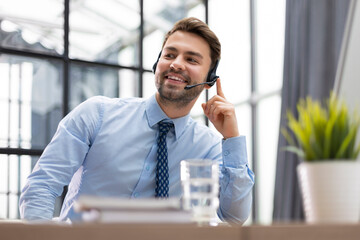 Smiling friendly handsome young male call centre operator.