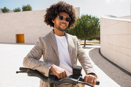 Content African American man riding bicycle. Male model with curly hair in suit with modern bicycle. Active lifestyle concept