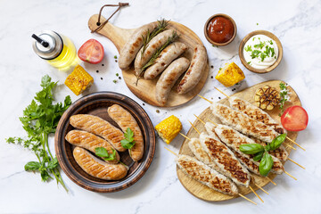 Summer party food. Grill food menu. Various bbq grilled sausages with fresh herbs and spices on marble tabletop. View from above.