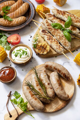 Summer party food. Grill food menu. Various bbq grilled sausages with fresh herbs and spices on marble tabletop.